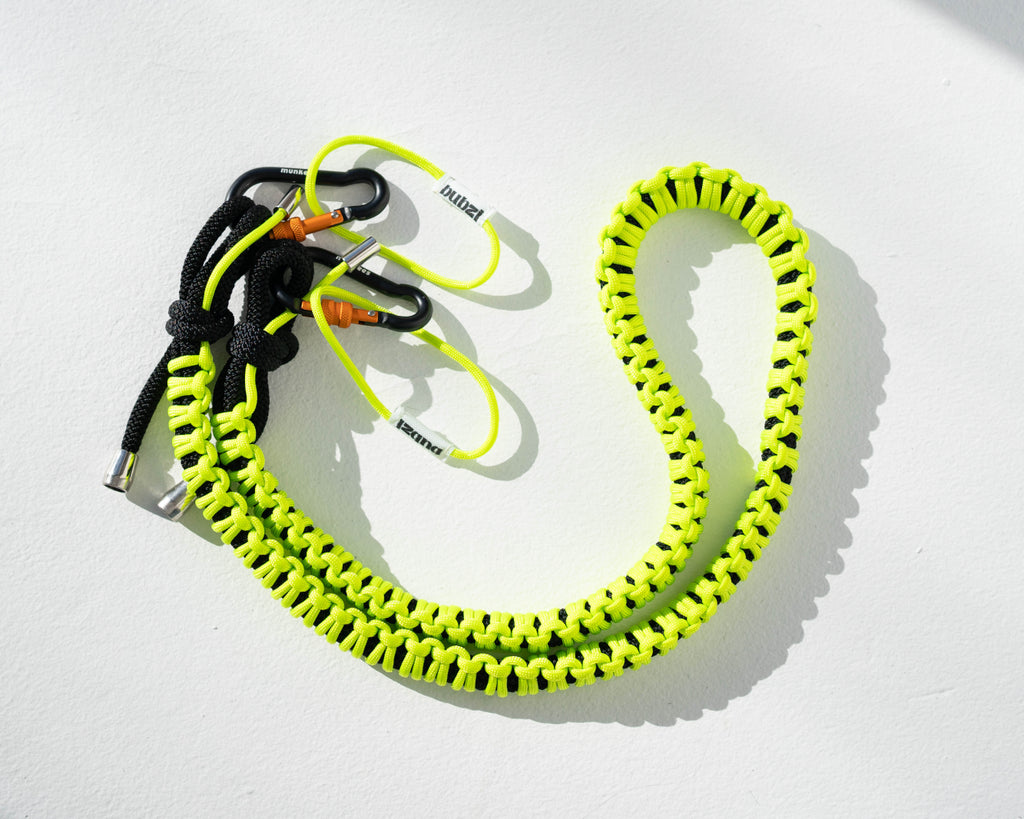 Black and lime Bubzi paracord camera strap with metal carabiners on a white background