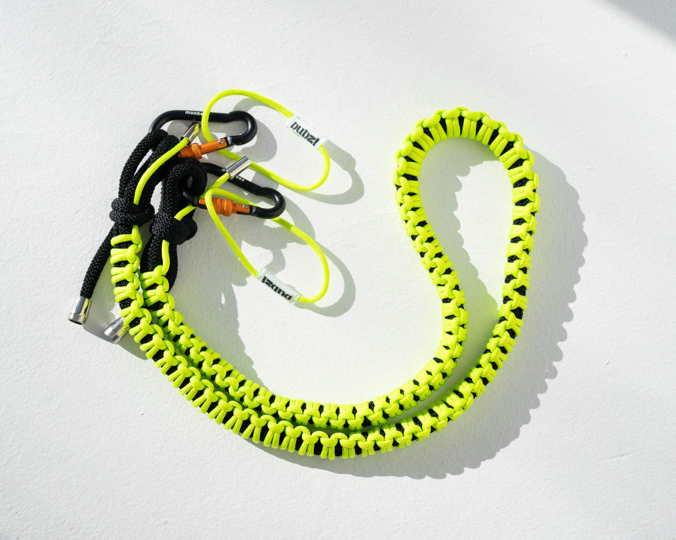 Black and lime Bubzi paracord camera strap with metal carabiners on a white background
