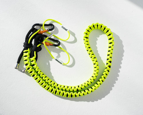 Black and lime Bubzi paracord camera strap with metal carabiners on a white background