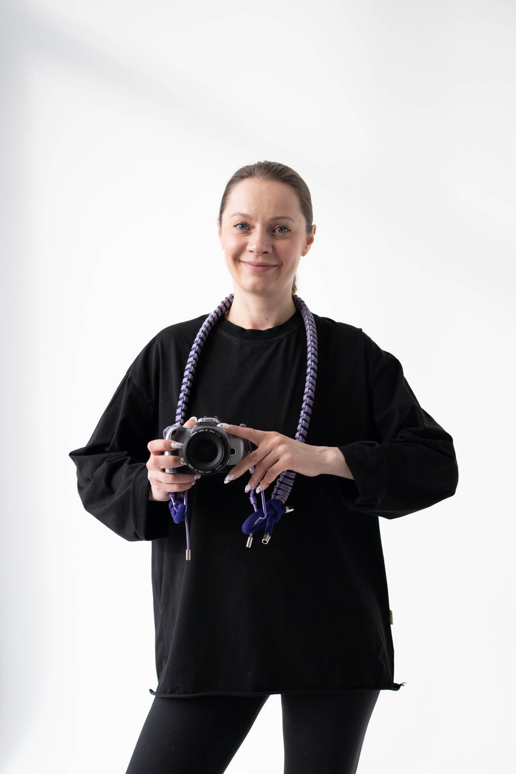 Model wearing a purple Bubzi camera strap attached to a compact camera