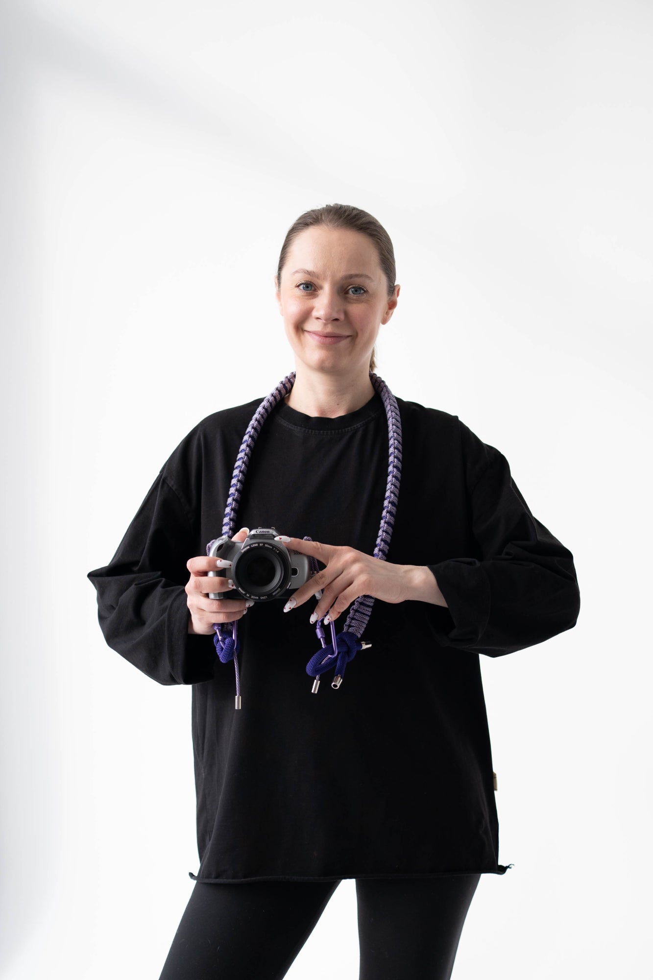Model wearing a purple Bubzi camera strap attached to a compact camera