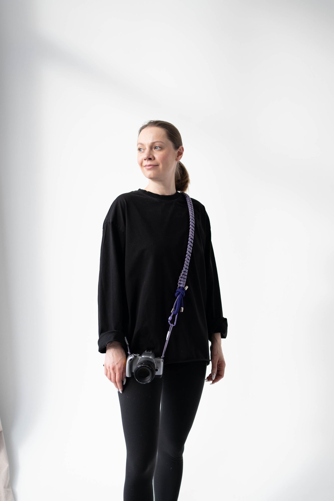 Model holding a camera with the purple Bubzi camera strap in a studio