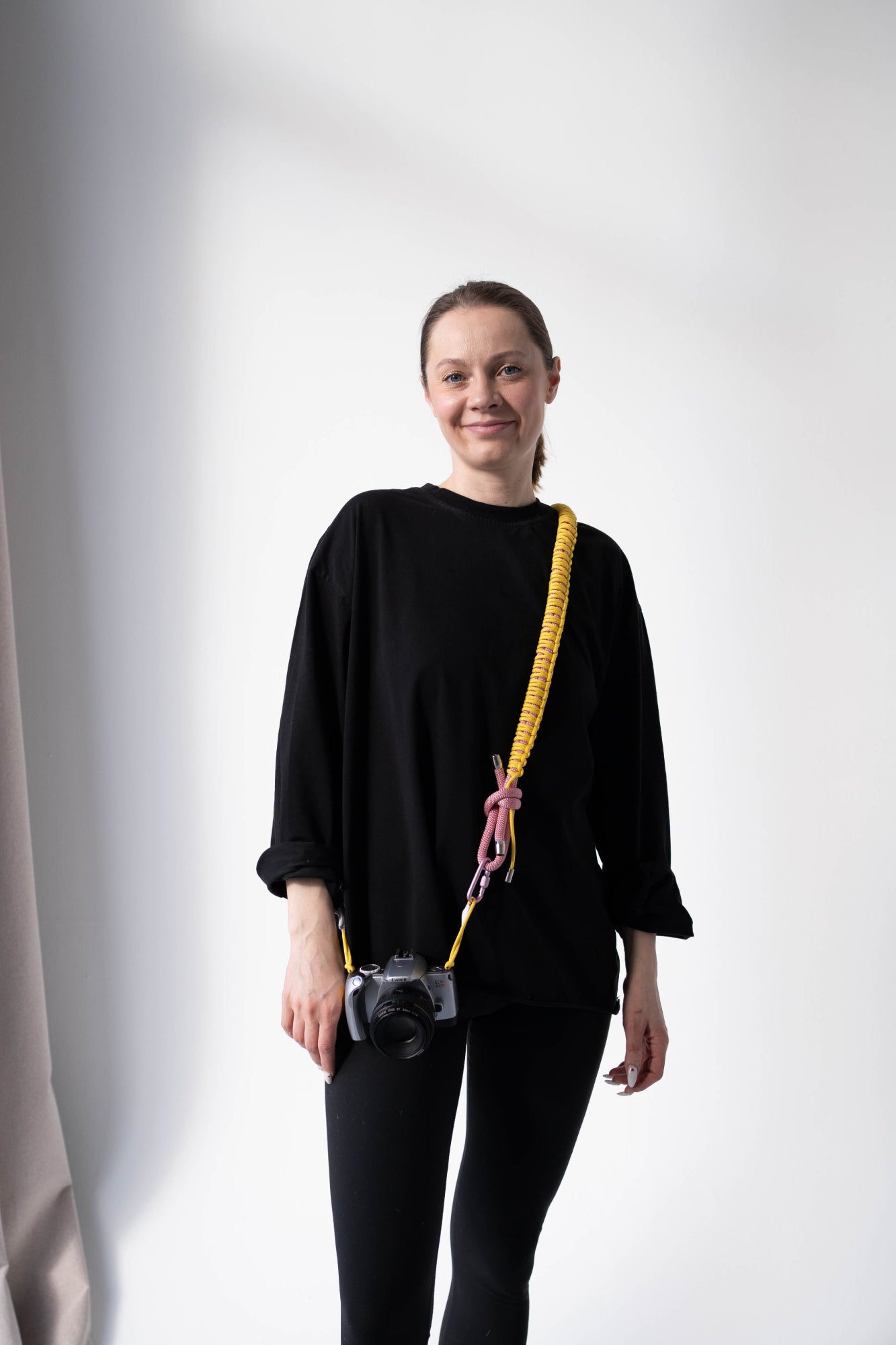 Model wearing the yellow and pink Bubzi camera strap with a compact camera
