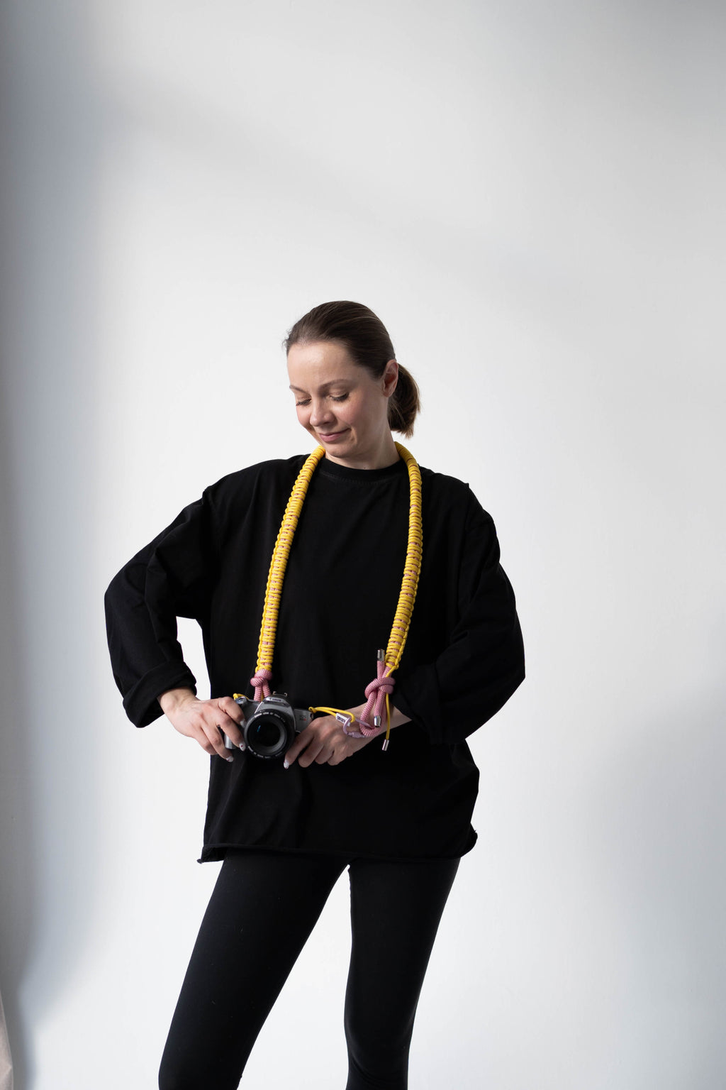 Model holding a camera with the yellow and pink Bubzi camera strap in a studio