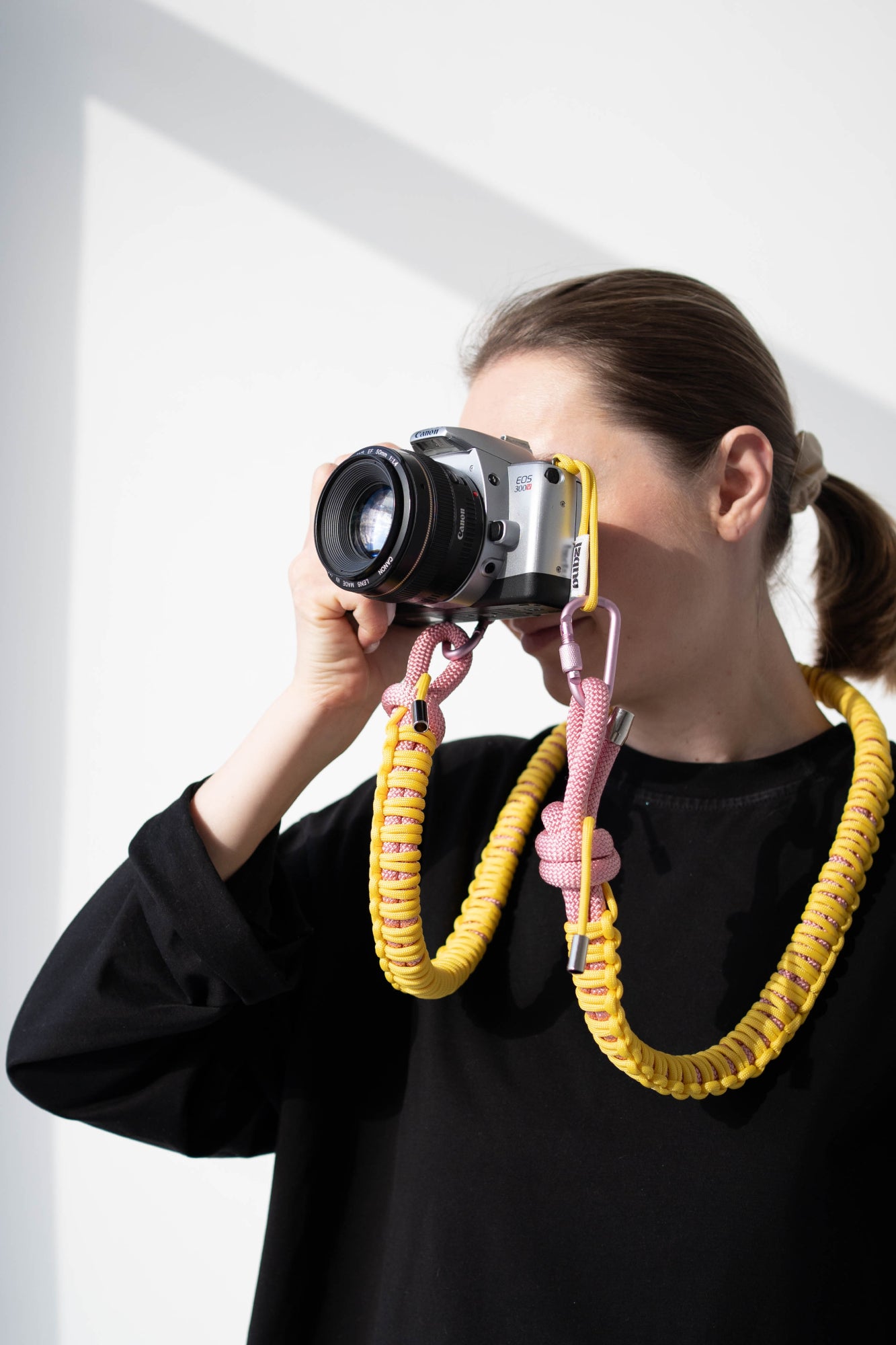Model using a camera with a yellow and pink Bubzi paracord strap