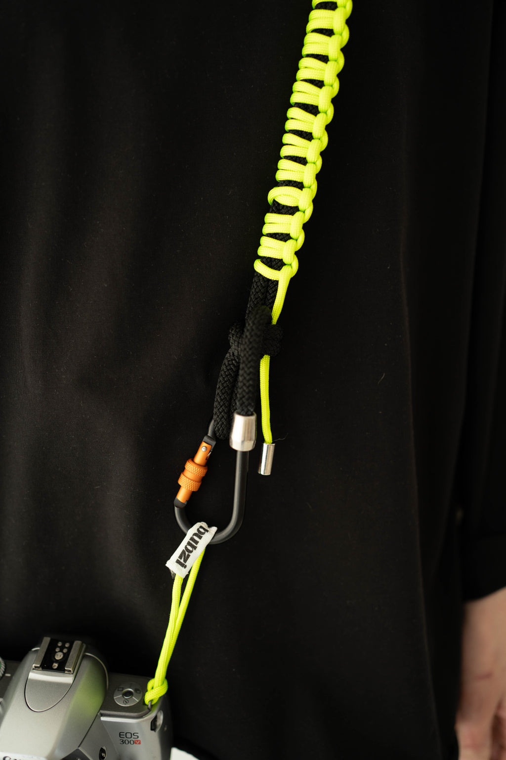 Front view of a model wearing the black and lime Bubzi camera strap with a camera