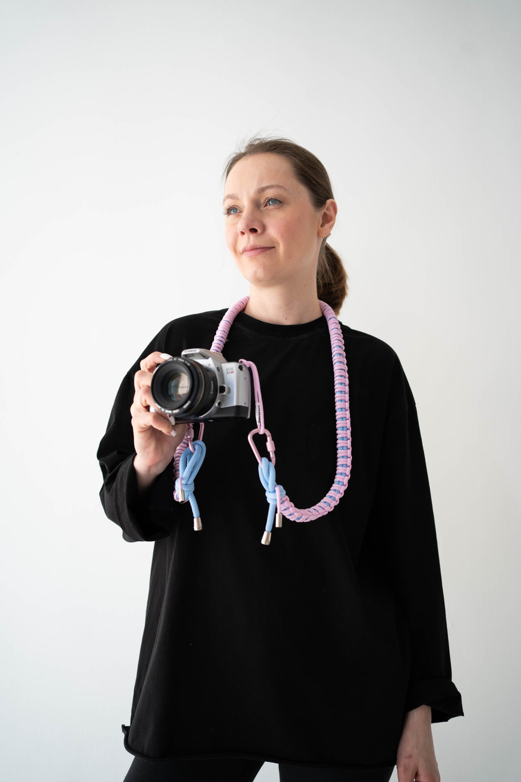 Model wearing a pink and blue Bubzi camera strap attached to a compact camera