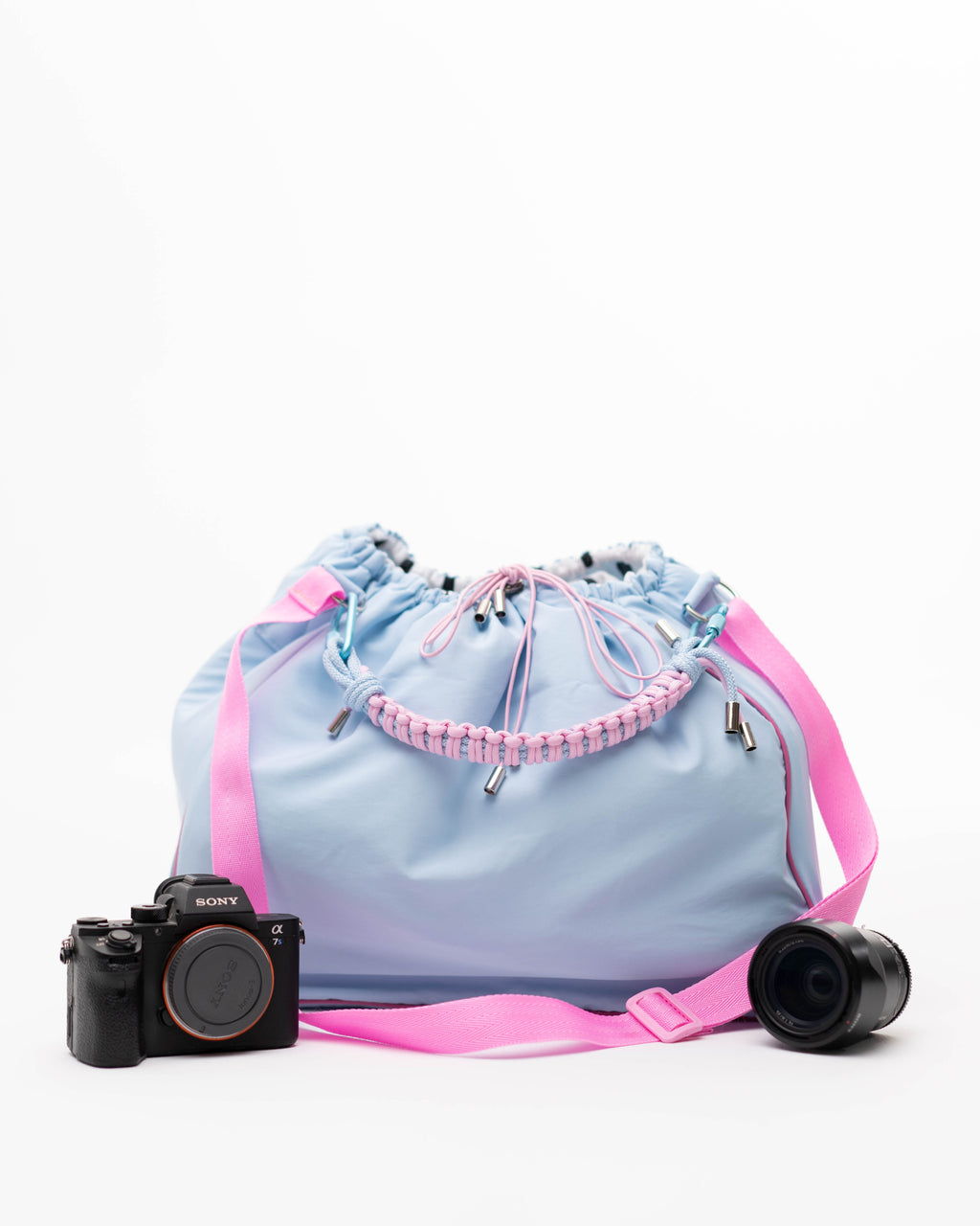 Light blue Maxi Bubzi bag with a pink strap next to a Sony camera and a lens.