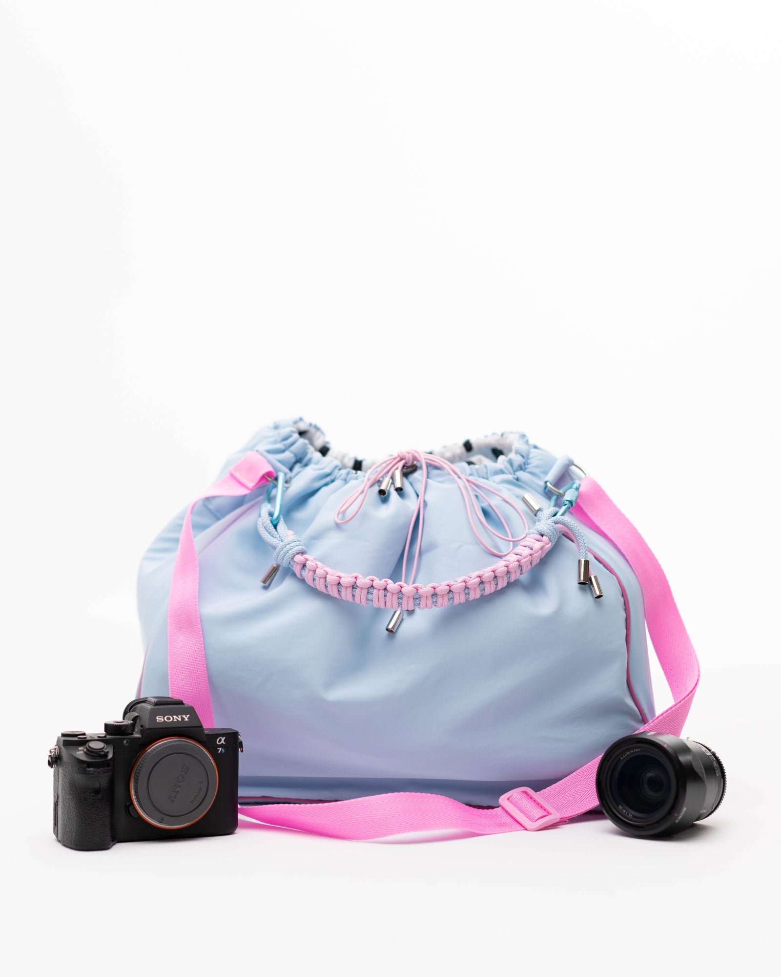 Light blue Maxi Bubzi bag with a pink strap next to a Sony camera and a lens.