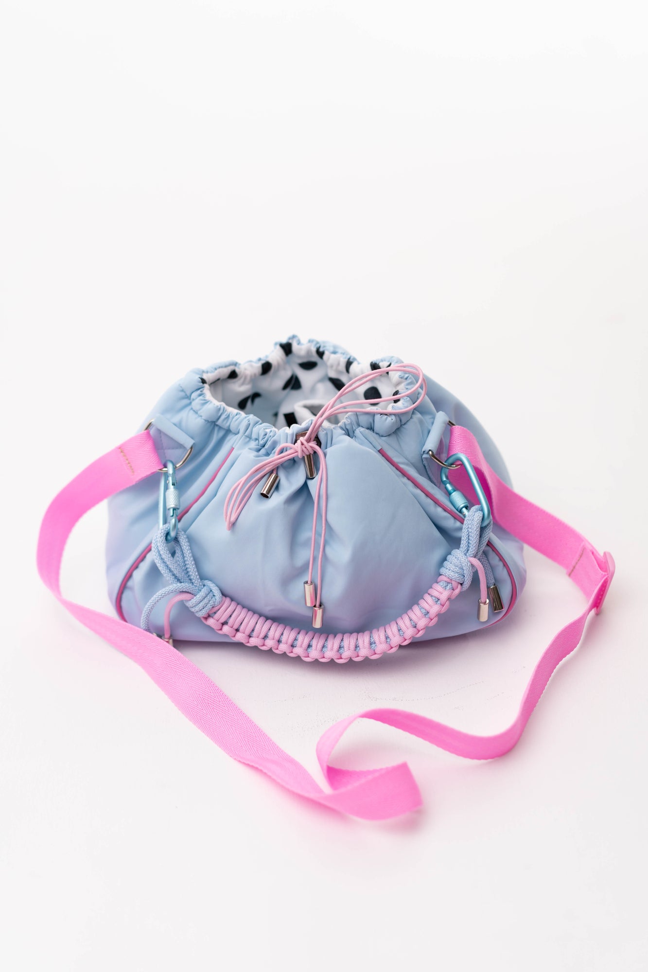 Front view of the blue Mini Bubzi bag with pink strap, braided handle, and polka dot lining