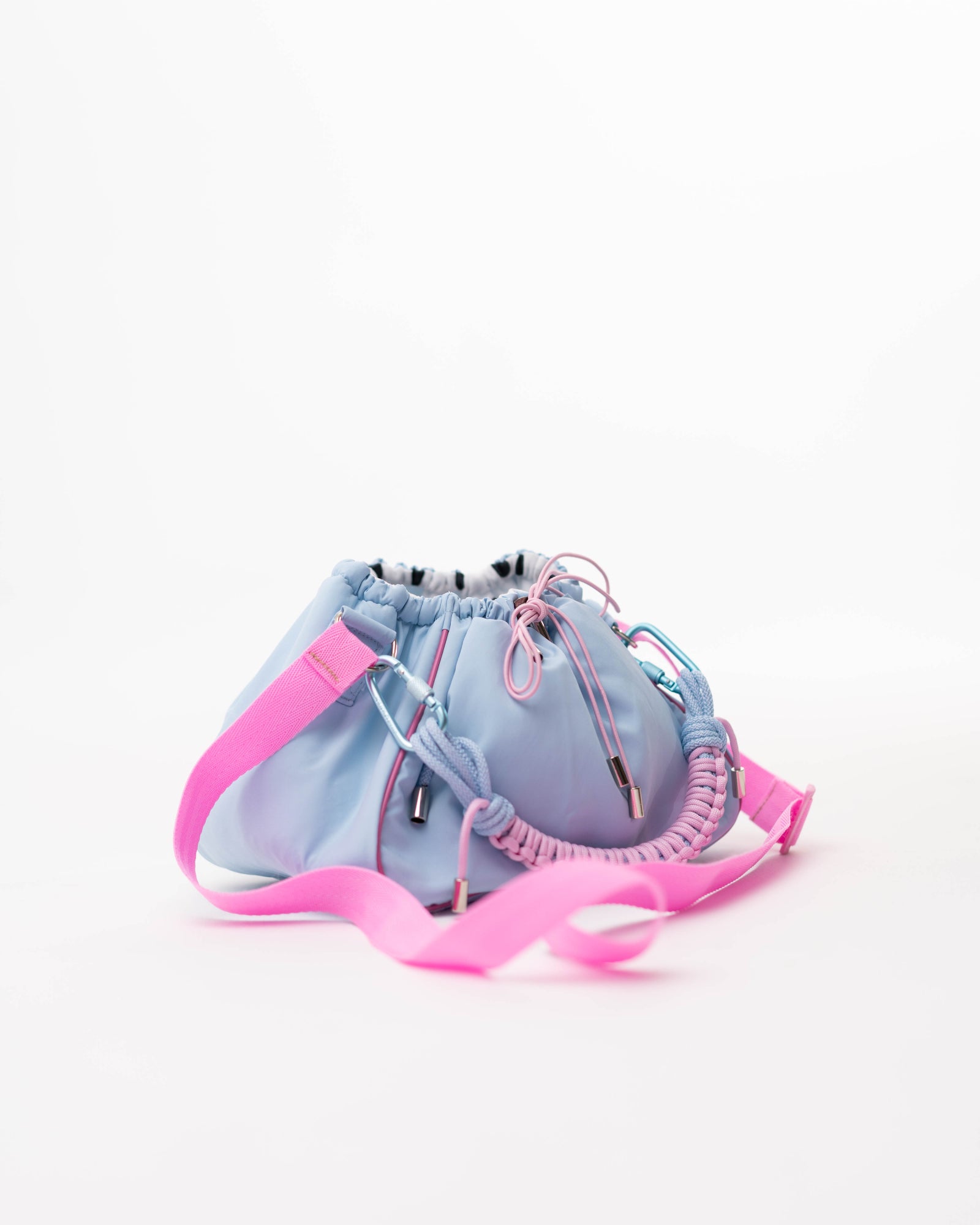 Side view of the blue Mini Bubzi bag with pink shoulder strap and soft rounded shape