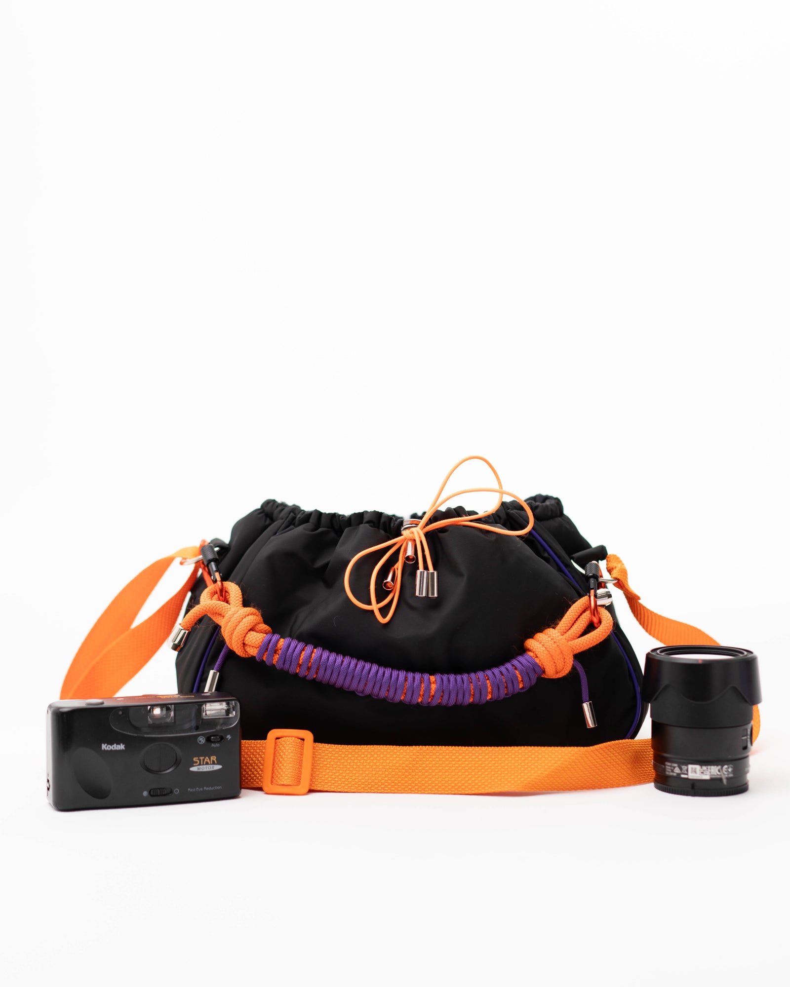 Close-up of the black Mini Bubzi bag with orange drawstrings, purple handle, and soft lining