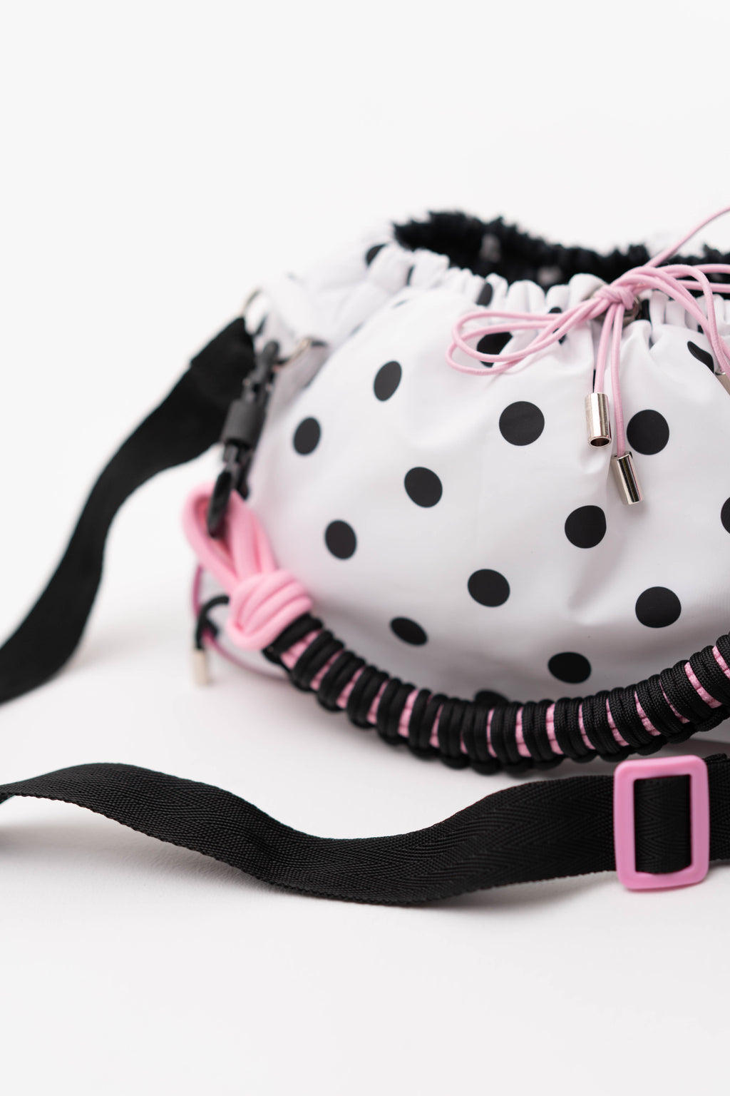 Close-up of the polka dot Mini Bubzi bag with pink drawstrings, black strap, and textured handle