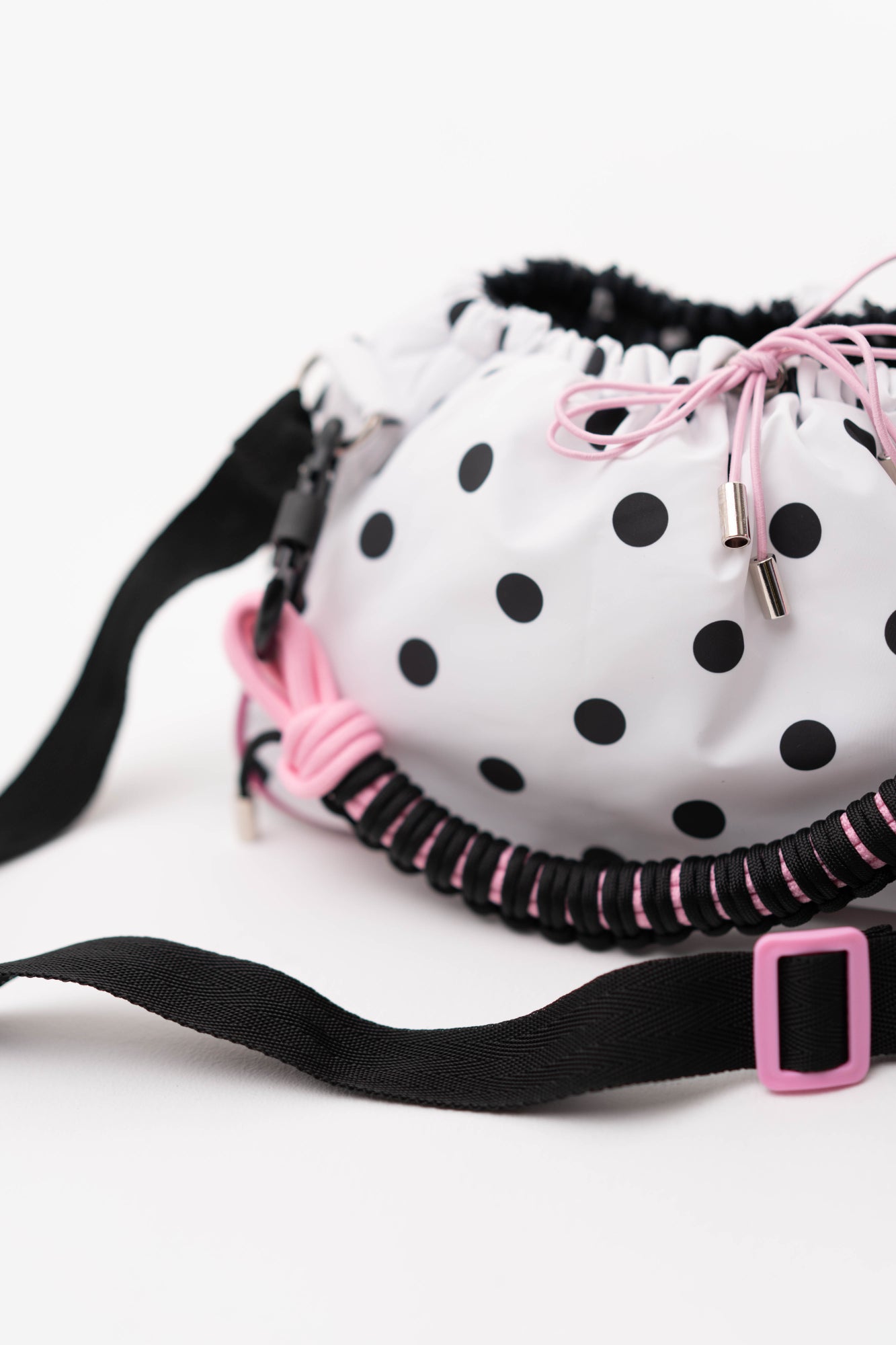 Close-up of the polka dot Mini Bubzi bag with pink drawstrings, black strap, and textured handle