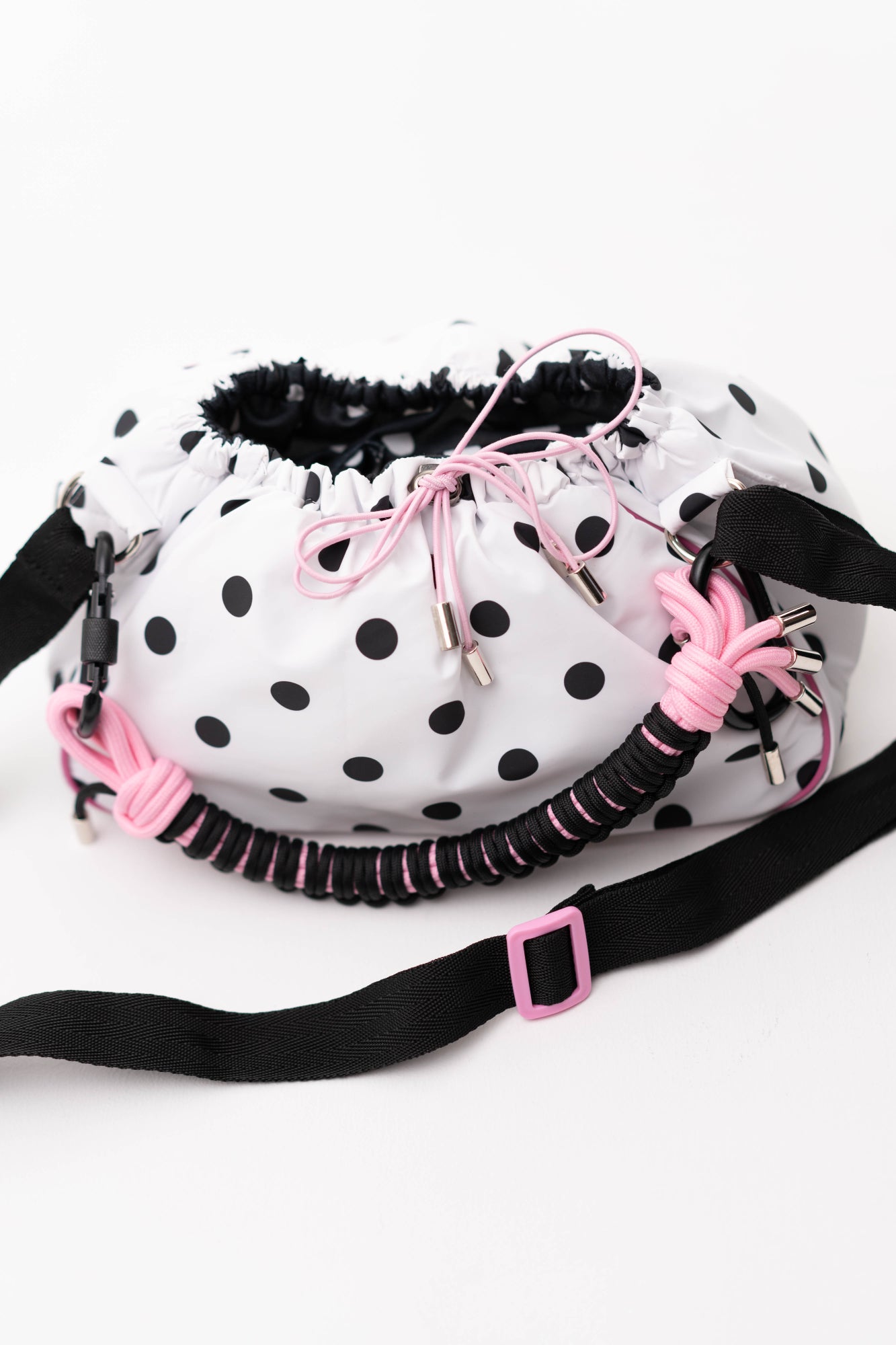 Detail view of the polka dot Mini Bubzi bag with pink cord accents, black strap, and soft gathered opening