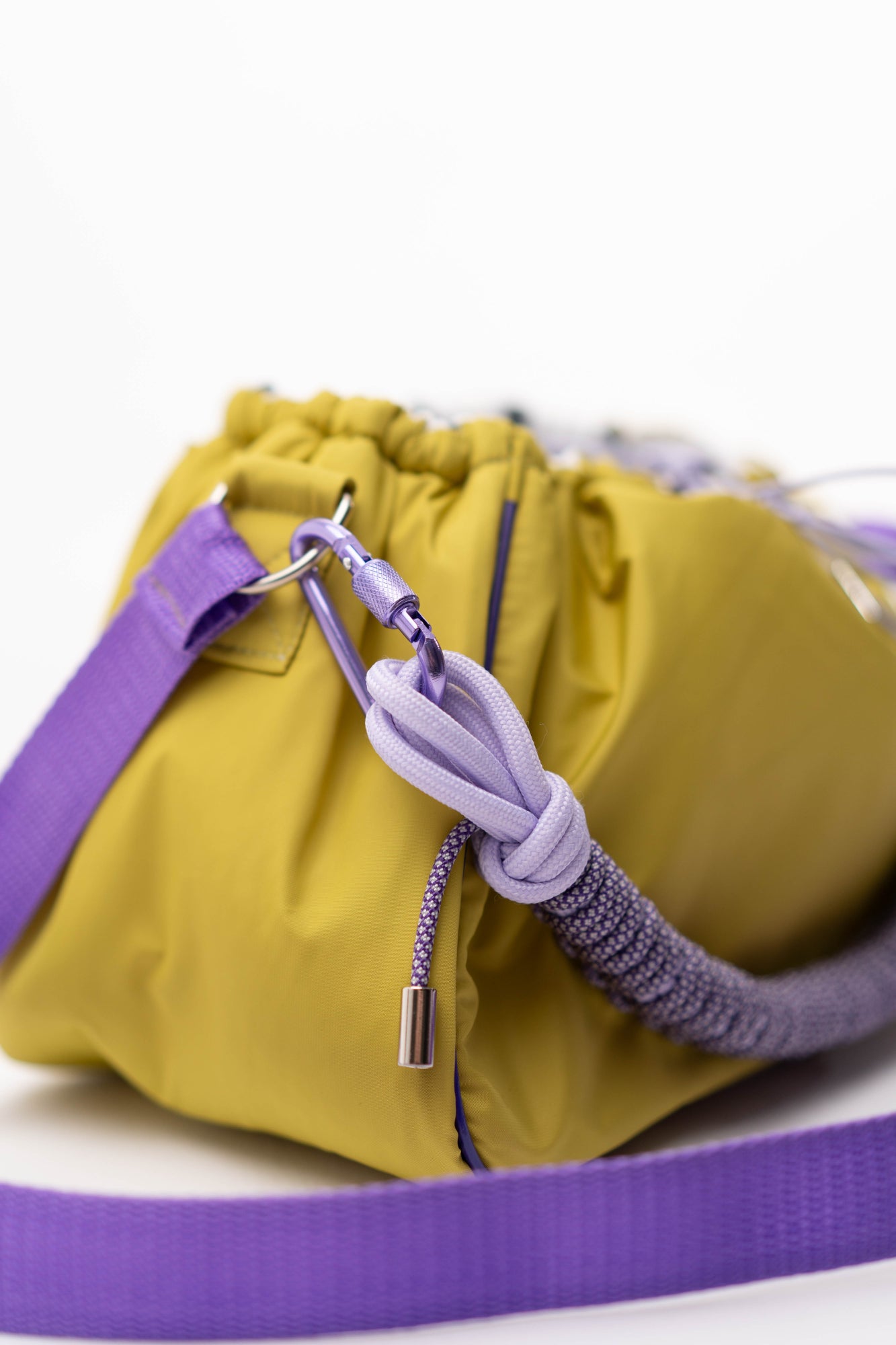 Close-up of the lime Mini Bubzi bag with purple drawstrings, soft lining, and paracord handle