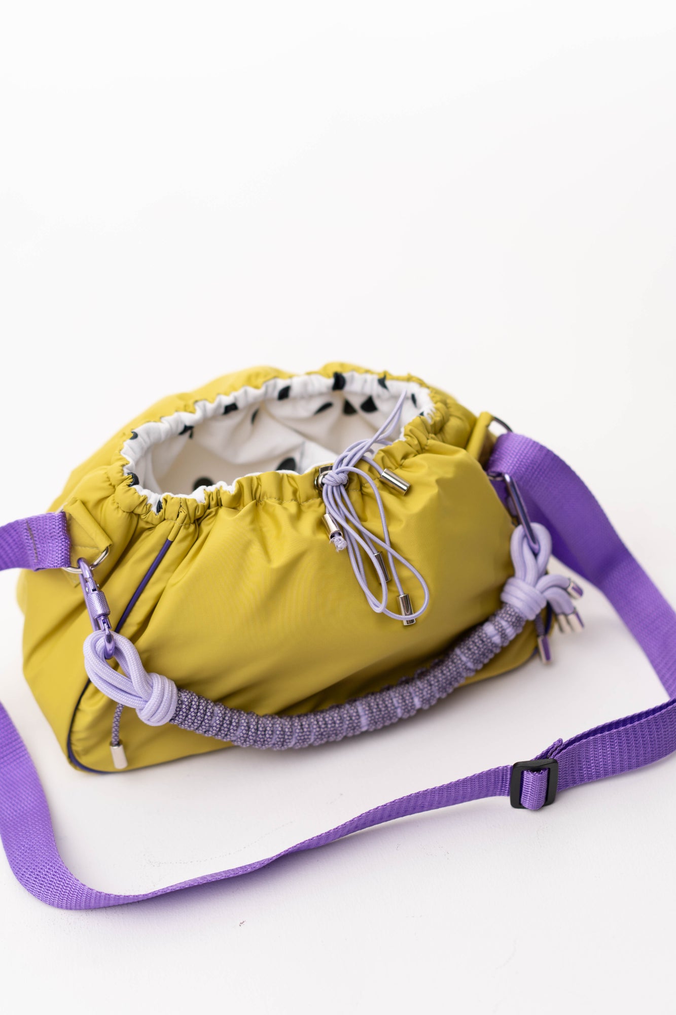 Side view of the lime Mini Bubzi bag with purple shoulder strap and compact rounded shape
