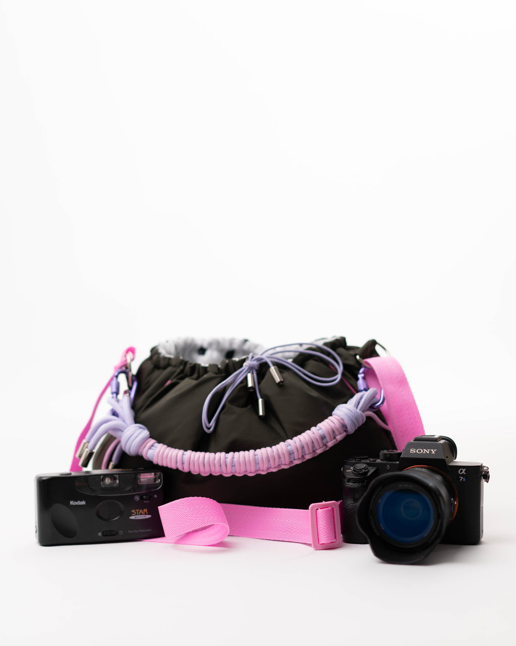 Khaki Mini Bubzi bag placed next to Kodak and Sony cameras on a white background