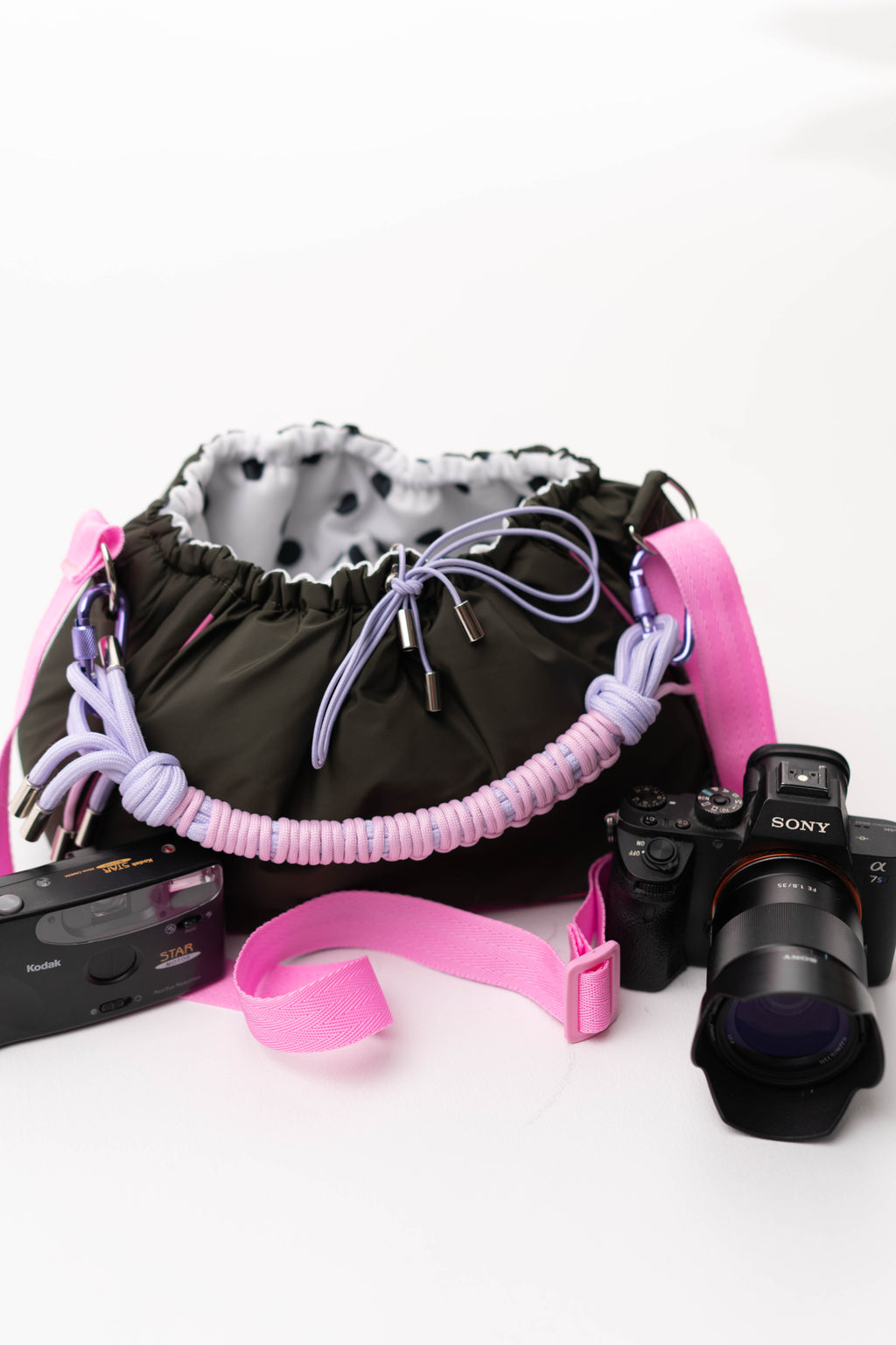 Khaki Mini Bubzi camera bag with pink strap, braided handle, and cameras for photo shoots