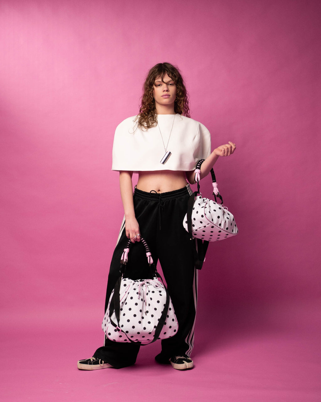 The model is holding two polka dot Maxi Bubzi bags against a pink background.