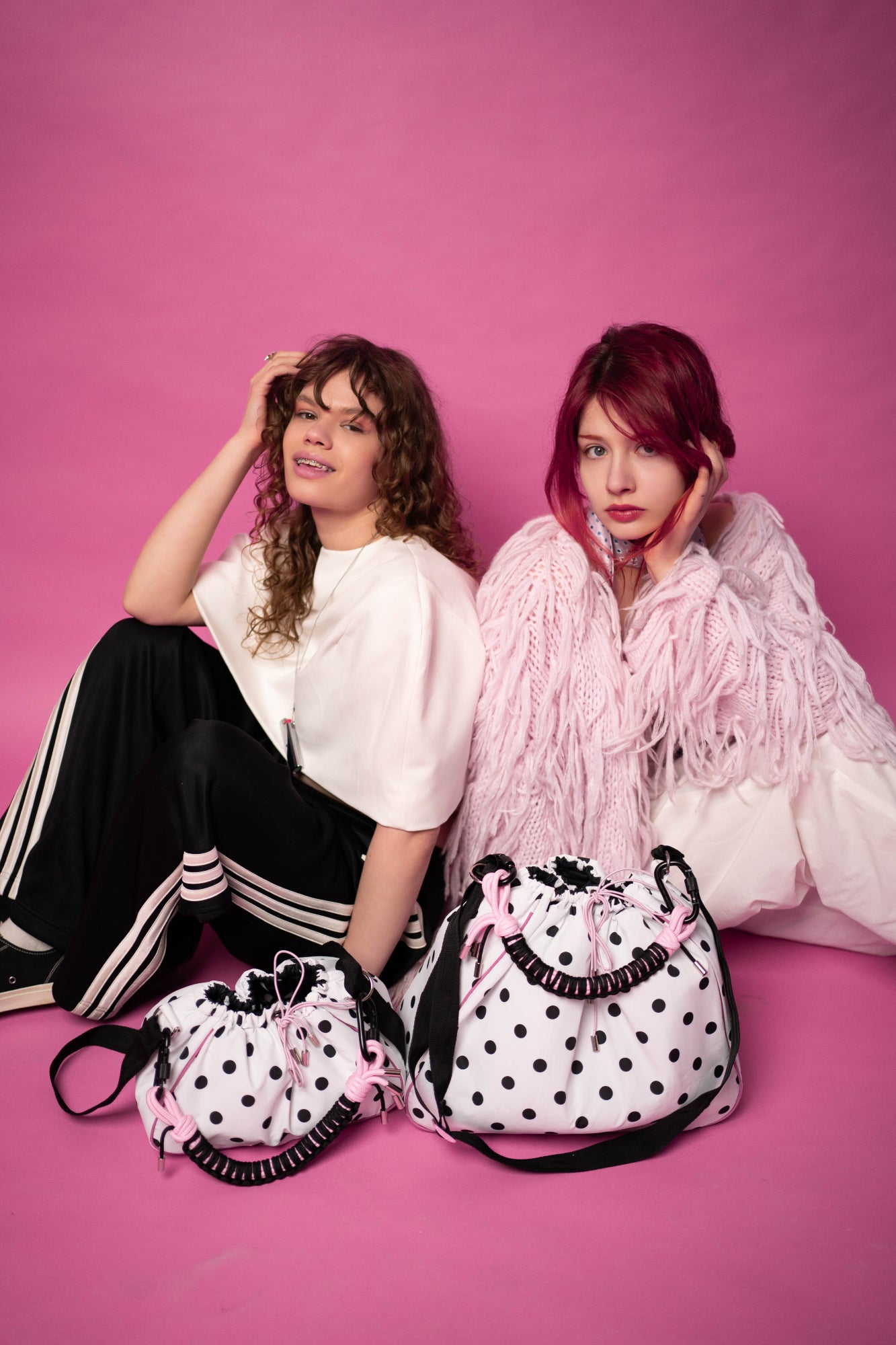 Two models with polka dot Maxi Bubzi bags against a pink studio background.