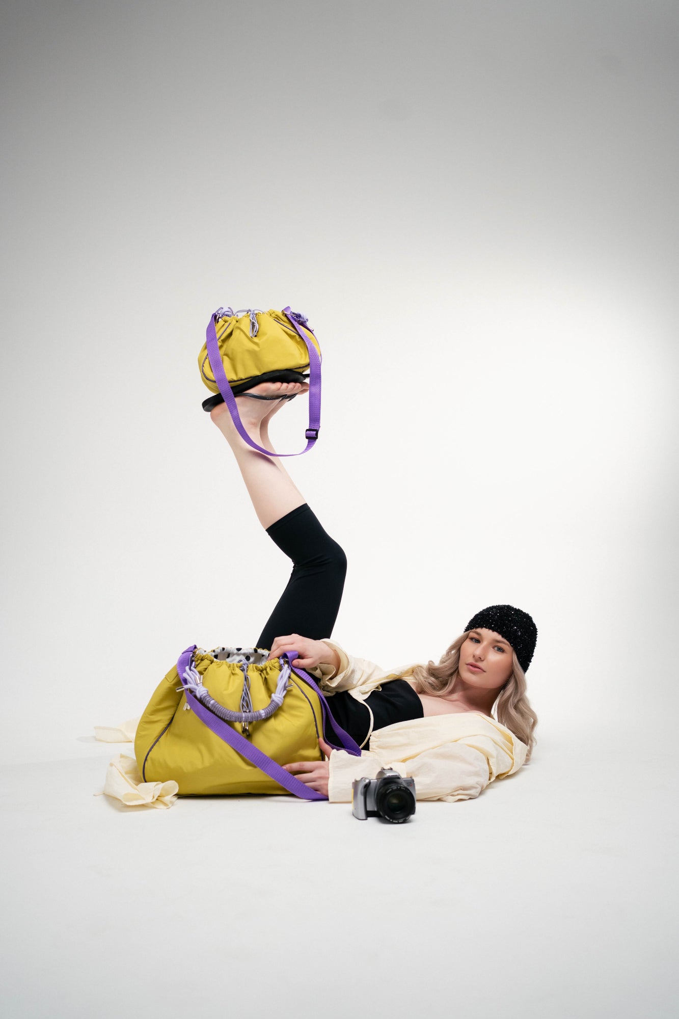 The model is lying next to a camera and two lime Maxi Bubzi bags.