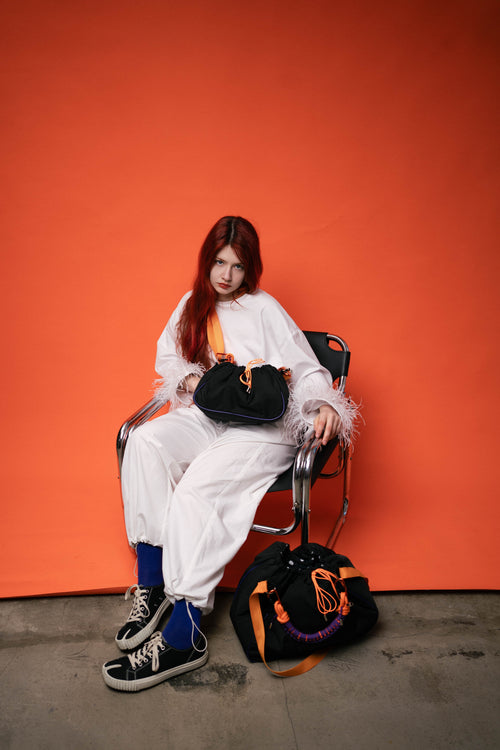 Model sitting with black Maxi Bubzi bags on an orange studio background
