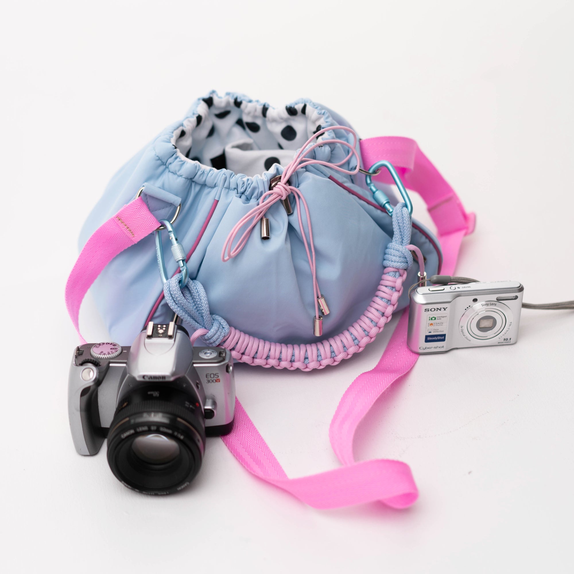 Blue Mini Bubzi camera bag with pink strap next to Canon and Sony cameras